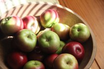 Tigela de maçãs saborosas frescas sobre mesa de madeira — Fotografia de Stock