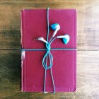 Concepto de libro de audio, auriculares envueltos alrededor de un libro viejo - foto de stock