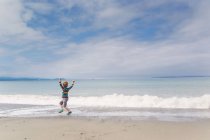 Rückansicht eines glücklichen Jungen, der am Strand spielt — Stockfoto