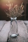 Скляна пляшка з польовими квітами на дерев'яному столі — стокове фото