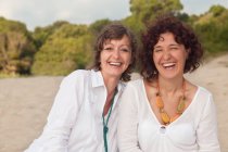 Portrait of two laughing mature women on beach — Stock Photo