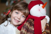 Portrait of smiling cute girl with snowman — Stock Photo