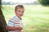 Портрет усміхненого хлопчика, що тримає кульбабу — стокове фото