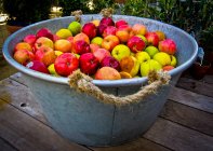 Tubful of apples on wooden table outdoors — Stock Photo