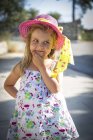 Маленька блондинка в літньому капелюсі стоїть з рукою на обличчі — стокове фото