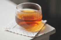 Glas Tee auf quadratischer Serviette an der Tischecke — Stockfoto