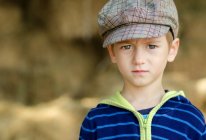 Retrato de um menino sério usando chapéu de pé ao ar livre — Fotografia de Stock