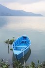 Barca a remi blu ancorata nel lago con sagoma di montagna sullo sfondo. Nepal, Regione occidentale, Zona di Gandaki, Pokhara, Mansawar, Lago di Phewa — Foto stock