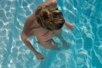 Joven rubia de pie en una piscina - foto de stock