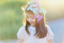 Smiling girl with butterflies in hair looking down outdoors — Stock Photo