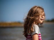 Retrato de uma menina com o cabelo varrido pelo vento em pé na estrada — Fotografia de Stock