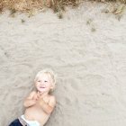 Criança deitada na praia — Fotografia de Stock