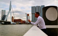 Netherlands, Rotterdam, Businessman using smartphone on waterfront — Stock Photo
