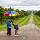 Dos hermanos jugando con paraguas en Windsor Great Park - foto de stock