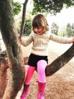 Kleines Mädchen in rosa Stiefeln klettert auf Baum — Stockfoto