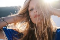 Портрет блондинки, яка біжить торкаючись волосся на сонячному світлі — стокове фото