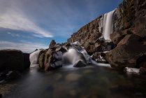 Islândia, Parque Nacional Azingvellir, Formação rochosa com tiro de cachoeira com longa exposição — Fotografia de Stock