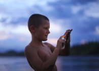 Хлопчик фотографує на пляжі в сутінках — стокове фото