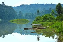 Indonesia, Sukabumi, Situ Gunung, vista panorámica de la reflexión de la naturaleza en el río con barco - foto de stock