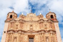 Facade of Santo Domingo church against cloudy sky,, San Cristobal de Las Casas, Chiapa, Mexico — стоковое фото
