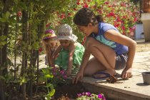 Madre e figlie trascorrono del tempo in giardino con fiori — Foto stock