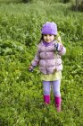 Портрет маленької дівчинки, що тримає вибрані лісові квіти на відкритому повітрі — стокове фото