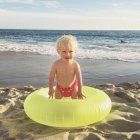 Niño en anillo de goma en la playa - foto de stock