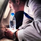 Крупный план пилота, держащего бутылку воды и смотрящего в окно самолета — стоковое фото