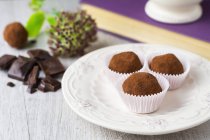 Tre tartufi di cioccolato su piatto bianco — Foto stock