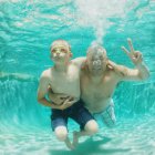Portrait of father and son swimming underwater in pool — Stock Photo