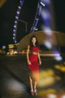 Сінгапур, жінка носить червоній сукні стоячи проти блискучих вогнів Singapore Flyer — стокове фото