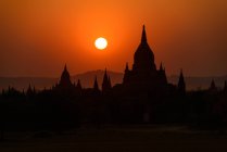 Vista panorámica de siluetas de templos durante la puesta del sol, Bagan, Myanmar - foto de stock