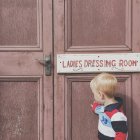 Boy standing outside ladies dressing room — Stock Photo