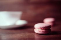 Pink tasty macaroons on wooden table, blurred background — Stock Photo