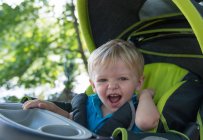 Bambino ragazzo ridendo mentre cavalca in passeggino — Foto stock