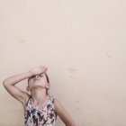 Портрет девушки с рукой на лбу у бежевой стены — стоковое фото