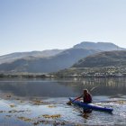 Reino Unido, Escócia, Homem sentado em canoa no lago — Fotografia de Stock