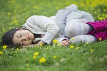 Chica acostada en la hierba con los ojos cerrados - foto de stock