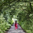 Woman wearing long dress walking down country lane — Stock Photo
