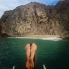 Donna che si tuffa in mare con scogliera sullo sfondo — Foto stock