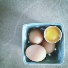 Box of fresh brown eggs with broken one — Stock Photo