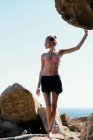 Жінка стоїть на скелях на пляжі і дивиться в бік — стокове фото