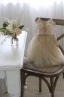 Vestido de ballet infantil en silla junto a jarrón de rosas - foto de stock