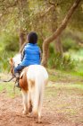 Маленький хлопчик верхи на поні коні в парку — стокове фото