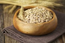 Organic rolled oats in wooden bowl — Stock Photo