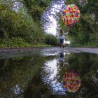 Girl holding balloons on path in countryside — Stock Photo