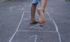 Immagine ritagliata del bambino che gioca a hopscotch in strada — Foto stock