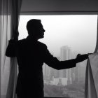 China, Hong Kong, homem de negócios desenhando cortinas na frente da janela com paisagem urbana — Fotografia de Stock