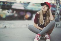 Junge selbstbewusste Frau sitzt auf einem Skateboard auf der Straße — Stockfoto