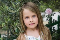 Портрет маленькой девочки с длинными волосами перед растениями — стоковое фото